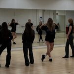 Gruppe von Jugendlichen übt Laufsteg-Posen im Tanzstudio vor einem Spiegel.