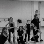 Sechs Mädchen posieren vor dem Spiegel im Tanzstudio.