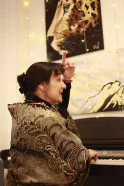 Eine Musiklehrerin erklärt etwas am Klavier.