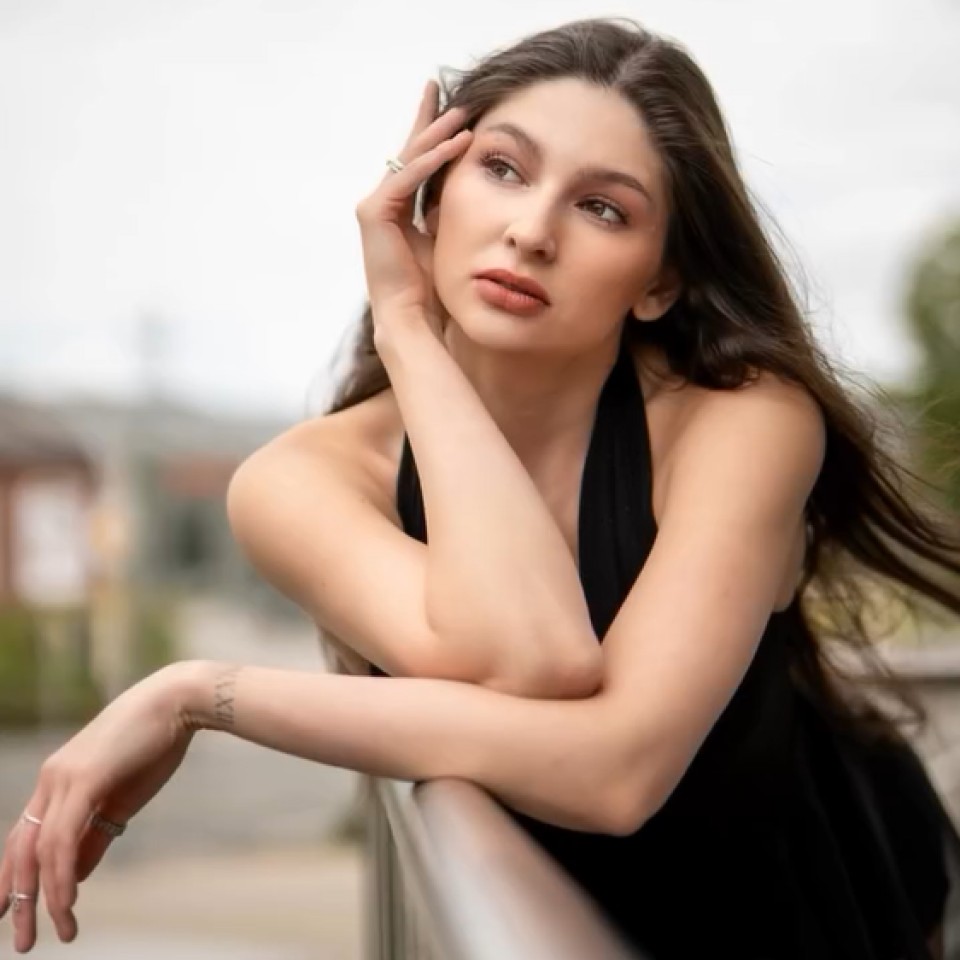 Eine Frau steht an das Geländer gelehnt.