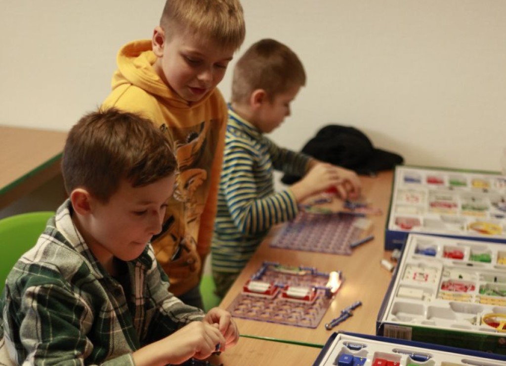 Drei Jungen bauen einfache Stromkreise mit Experimentierkästen.
