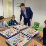 Педагог объясняет детям работу с электронными наборами за столом.