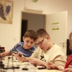 Двое мальчиков работают с паяльником и радиодеталями на занятии по электронике.