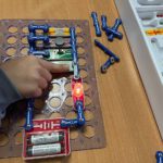 Рука ребёнка включает светодиод на плате Snap Circuits.