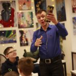 Преподаватель демонстрирует шумовой инструмент и рассказывает о звуке.