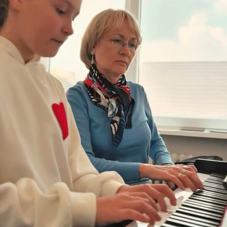 Eine Frau und ein Mädchen spielen gleichzeitig Klavier.