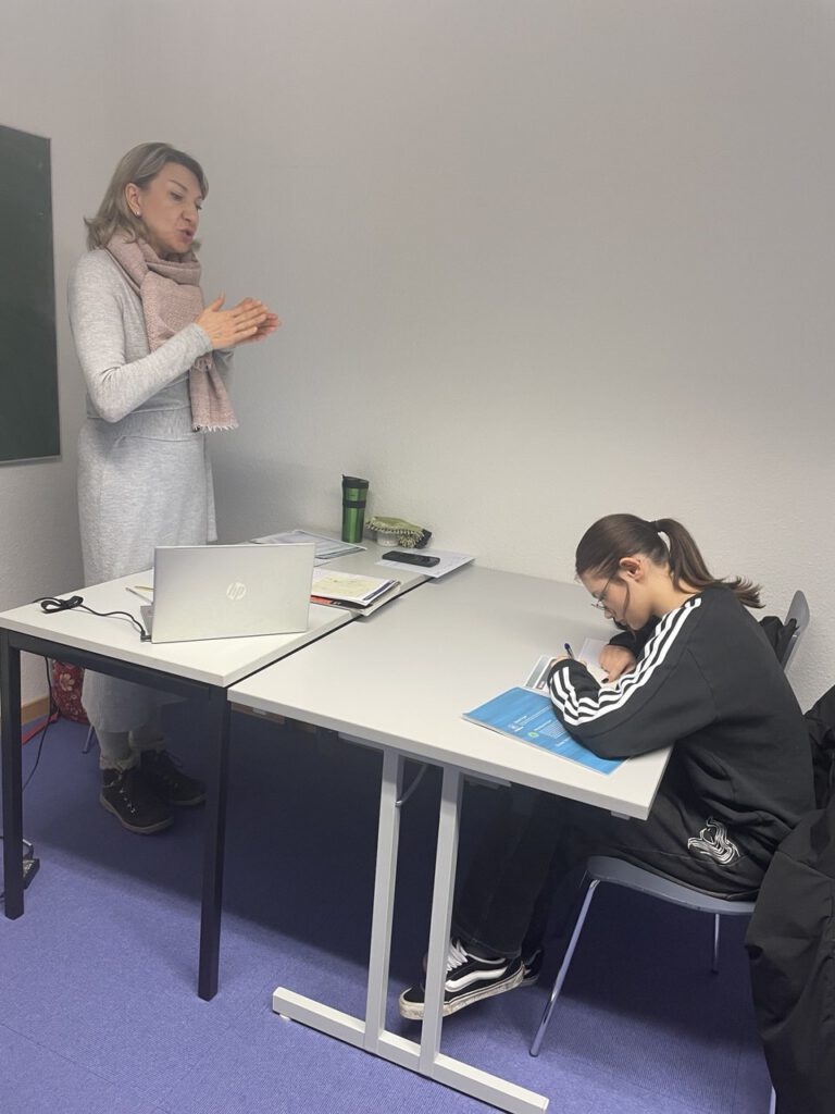 Lehrerin erklärt einer Schülerin Inhalte am Tisch.