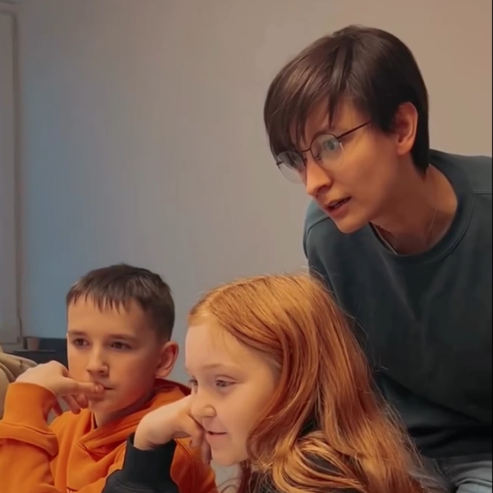 Eine Frau und zwei Schüler blicken während einer Programmierstunde interessiert auf den Bildschirm.