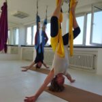 Umkehrhaltung im gelben Tuch, Arme seitlich ausgestreckt – sicher angeleitet.