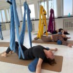 Entspannung: Teilnehmerinnen liegen auf Faszienrollen; Tücher hängen bereit.