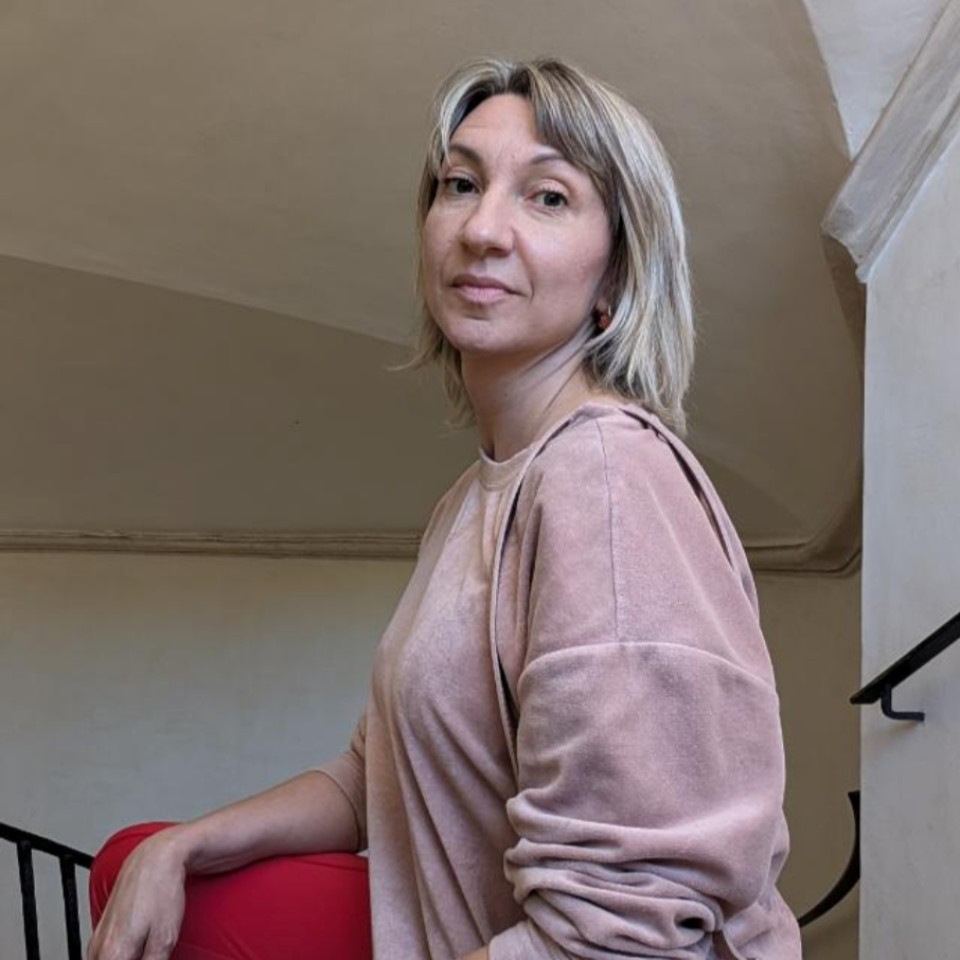 Eine Frau steht neben einer Treppe und lächelt.