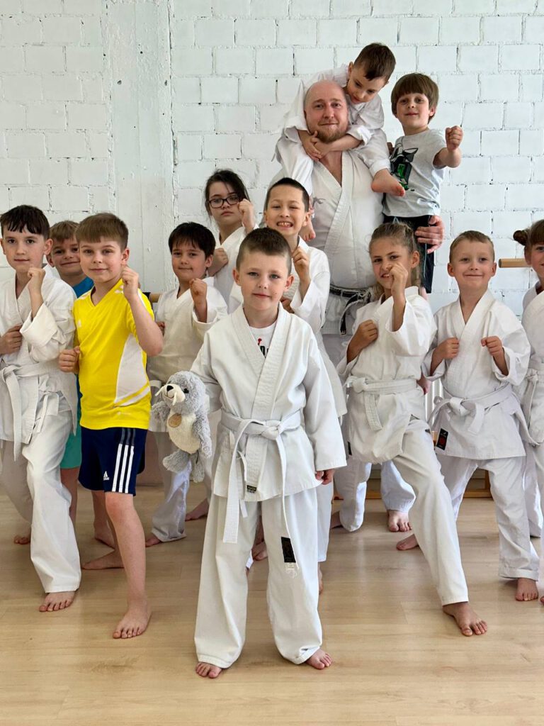 Kinderkarate-Gruppe mit Trainer; Kampfstellung, ein Kind mit Plüschtier.