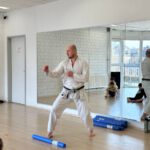 Тренер демонстрирует базовую технику и стойку в зале.