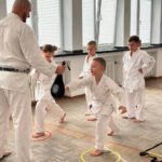 Тренер держит лапу; ребёнок отрабатывает удар, круги-метки на полу.