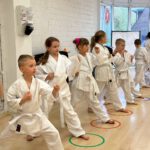 Дети отрабатывают стойки в ряд, цветные круги отмечают позиции.