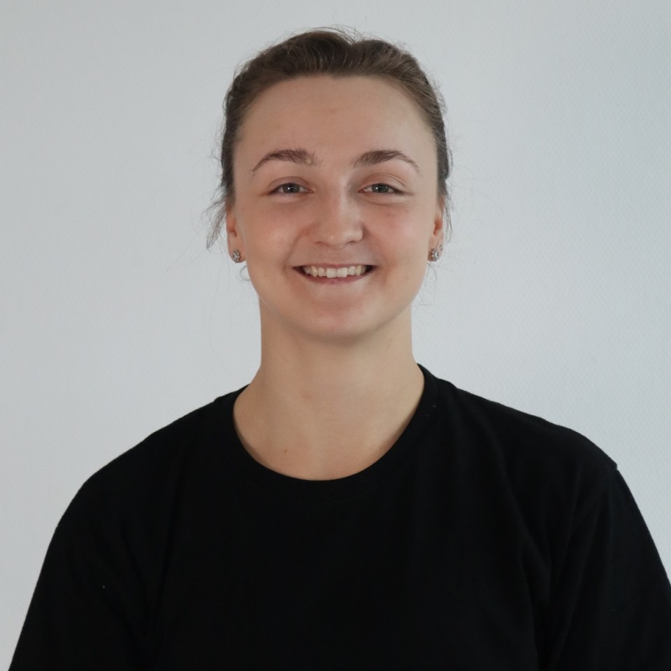 Eine junge Frau in einem schwarzen T-Shirt lächelt.