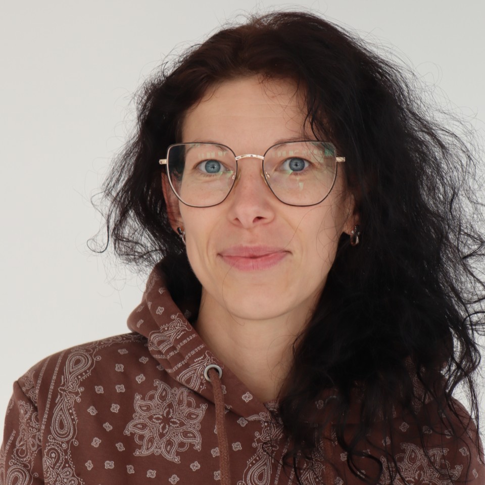 Frau mit Brille und langen dunklen Haaren lächelt