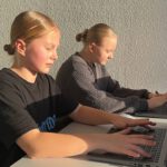 Zwei Schülerinnen arbeiten konzentriert am Laptop im Sonnenlicht im Programmierkurs.