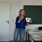 Преподаватель показывает карточки и объясняет новое слово на уроке русского.