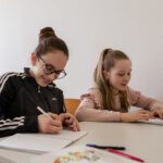 Две школьницы выполняют письменное задание на уроке русского языка.