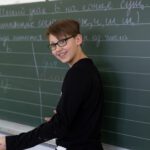 Мальчик пишет по-русски на доске, отрабатывая орфографию и почерк.