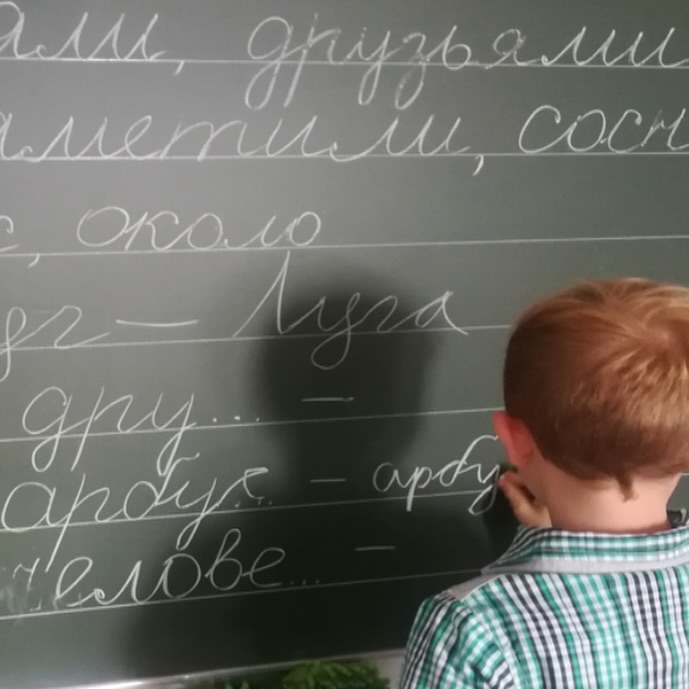 Schüler schreibt Russisch an die Tafel und übt Rechtschreibung und Schrift.