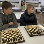 Zwei Jungen sitzen im Klassenraum vor ihren Schachbrettern und warten konzentriert auf den Spielbeginn.