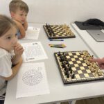 Zwei Kinder sitzen vor einem aufgebauten Schachbrett