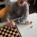 Junge richtet Schachfiguren ordentlich auf einem leeren Brett aus.