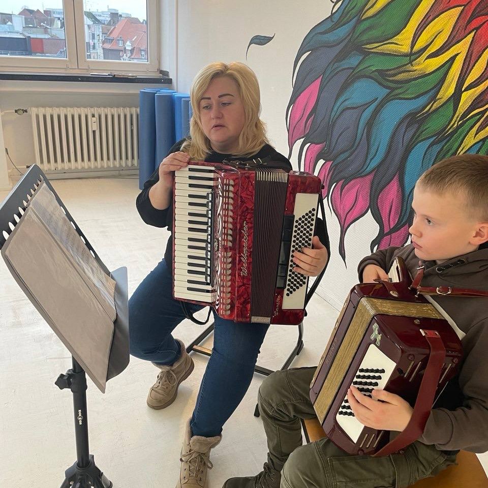 Eine Frau und ein Junge spielen Akkordeon.