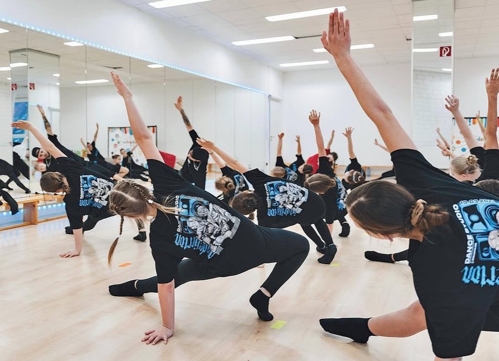 Kindergruppe beim Tanztraining mit Dehnübungen.