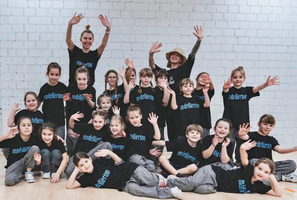 Kinder und Trainer posieren lachend nach dem Tanztraining.
