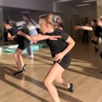 Девочки танцуют современную хореографию в танцевальном зале.