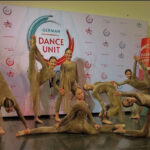 Танцевальная группа девочек в костюмах позирует на конкурсе.