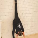 Девочка тренирует гибкость у стены на занятии по танцам.