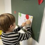 Мальчик прикрепляет карточки к доске по теме «Семья» на уроке.