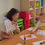 Урок украинского: учитель показывает карточки, мальчик делает задание-аппликацию.