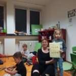 Педагог на оранжевых ковриках; дети строят из цветных палочек, девочка показывает рабочий лист.