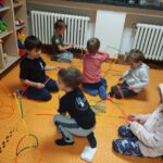 Дошкольники сидят на ковриках и вместе строят фигуры из цветных конструкторов-палочек.