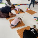 Упражнение на расслабление: дети лежат на ковриках, педагог держит вертушку; рядом дети играют с блоками.