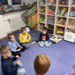 Круг общения: дети сидят полукругом и слушают педагога на занятии по русскому языку.