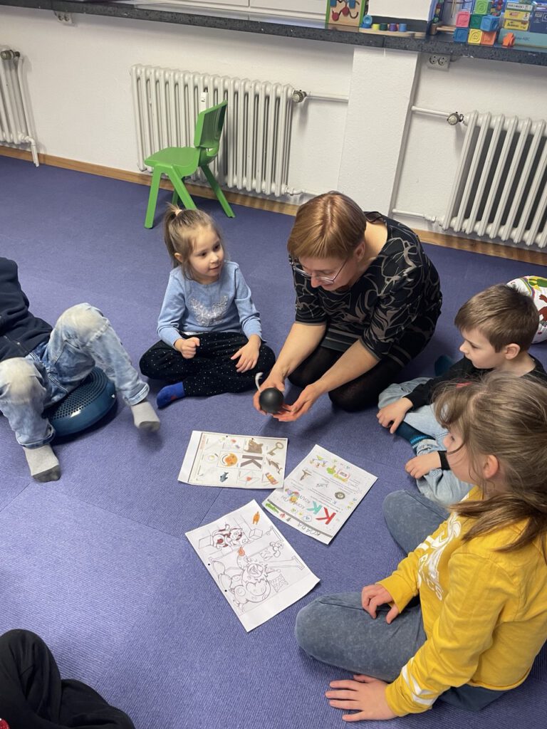 Laut- und Buchstabenspiel: Gruppe auf dem Teppich bearbeitet Russisch-Aufgaben.