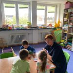 Настольная игра с карточками: педагог и трое детей тренируют слова и звуки по-русски.