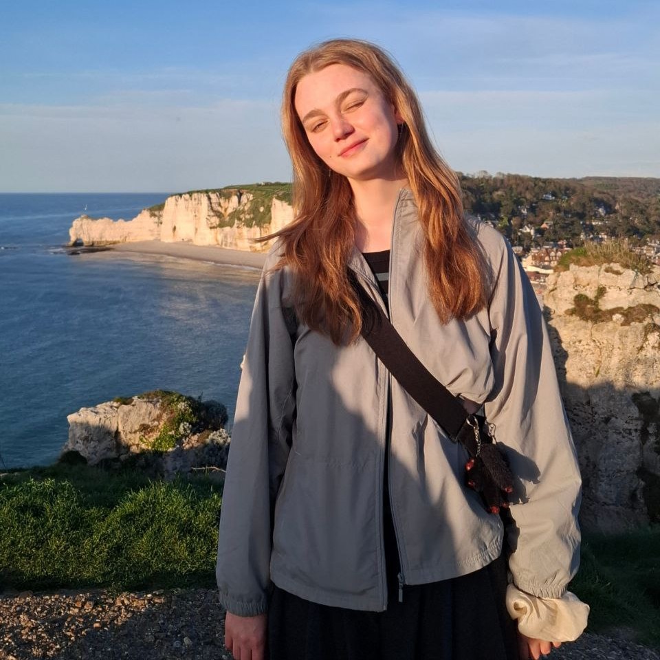 Das Mädchen steht vor dem Hintergrund des Meeres und lächelt.